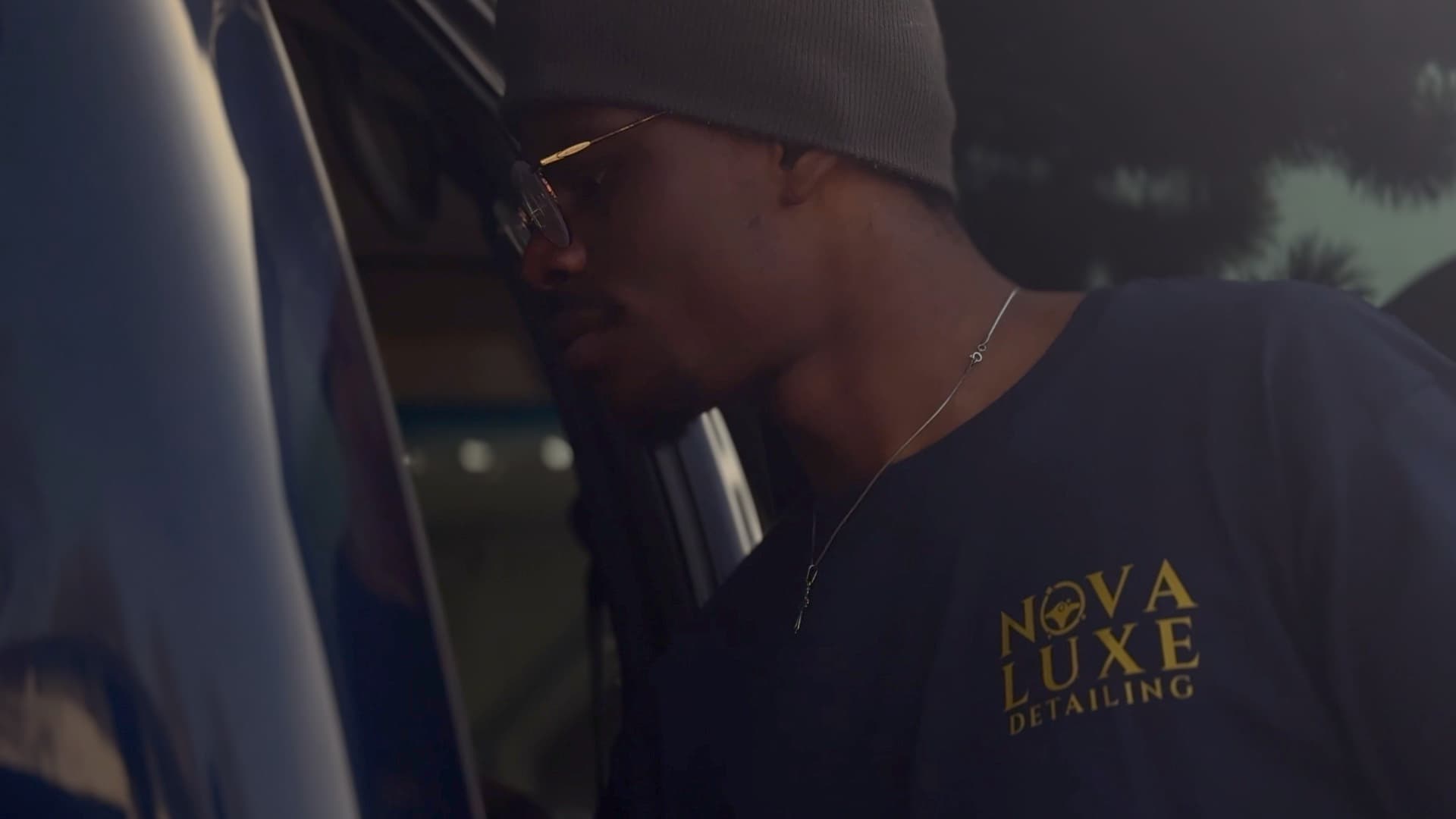 A Nova Luxe detailer at work beside a vehicle at golden hour